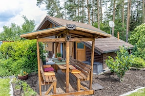 Una cabaña de madera con porche, mobiliario exterior y un pequeño jardín.