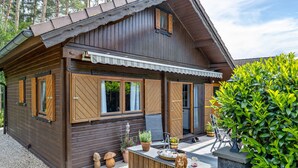 A wooden cabin with a porch, a small outdoor seating area, and a well-maintained garden. - Holiday Home Obert - Drognitz with Private Terrace, Garden, Free Boat Use and Wi-Fi (Drognitz)