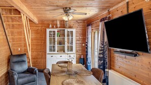 A wooden interior with a dining table, chairs, a television, and a cabinet with glass doors. - Holiday Home Obert - Drognitz with Private Terrace, Garden, Free Boat Use and Wi-Fi (Drognitz)