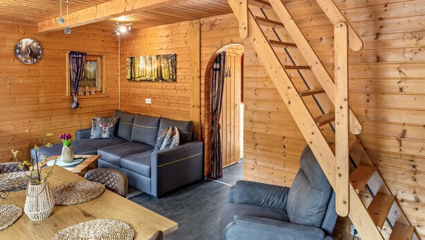 A wooden interior with a sofa, a table with a vase, and a staircase. - Holiday Home Obert - Drognitz with Private Terrace, Garden, Free Boat Use and Wi-Fi (Drognitz)