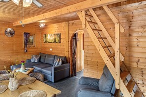 Un interior de madera con un sofá, una mesa con un jarrón y una escalera.