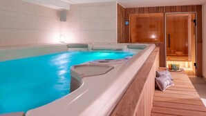 Ein Wellnessbereich mit Whirlpool, Holzliegen und einer Sauna.