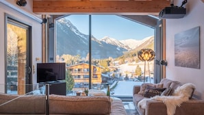 Ein modernes Wohnzimmer mit einem großen Fenster, einem Flachbildfernseher und einem gemütlichen Sofa.