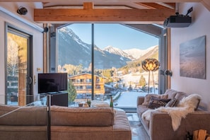 A modern living room with a large window, a flat-screen TV, and a cozy sofa.