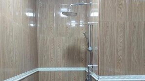 A small, tiled shower room with wooden paneling and a showerhead. - Oi Beach (Maamigili)