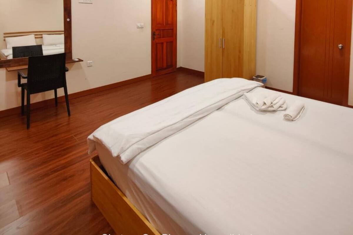 Une chambre à coucher avec un lit en bois, une armoire en bois, un bureau avec une chaise et un miroir.