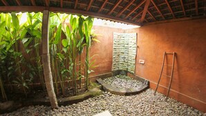 A room with a stone wall, a wooden ladder, and a small garden area with plants and pebbles.