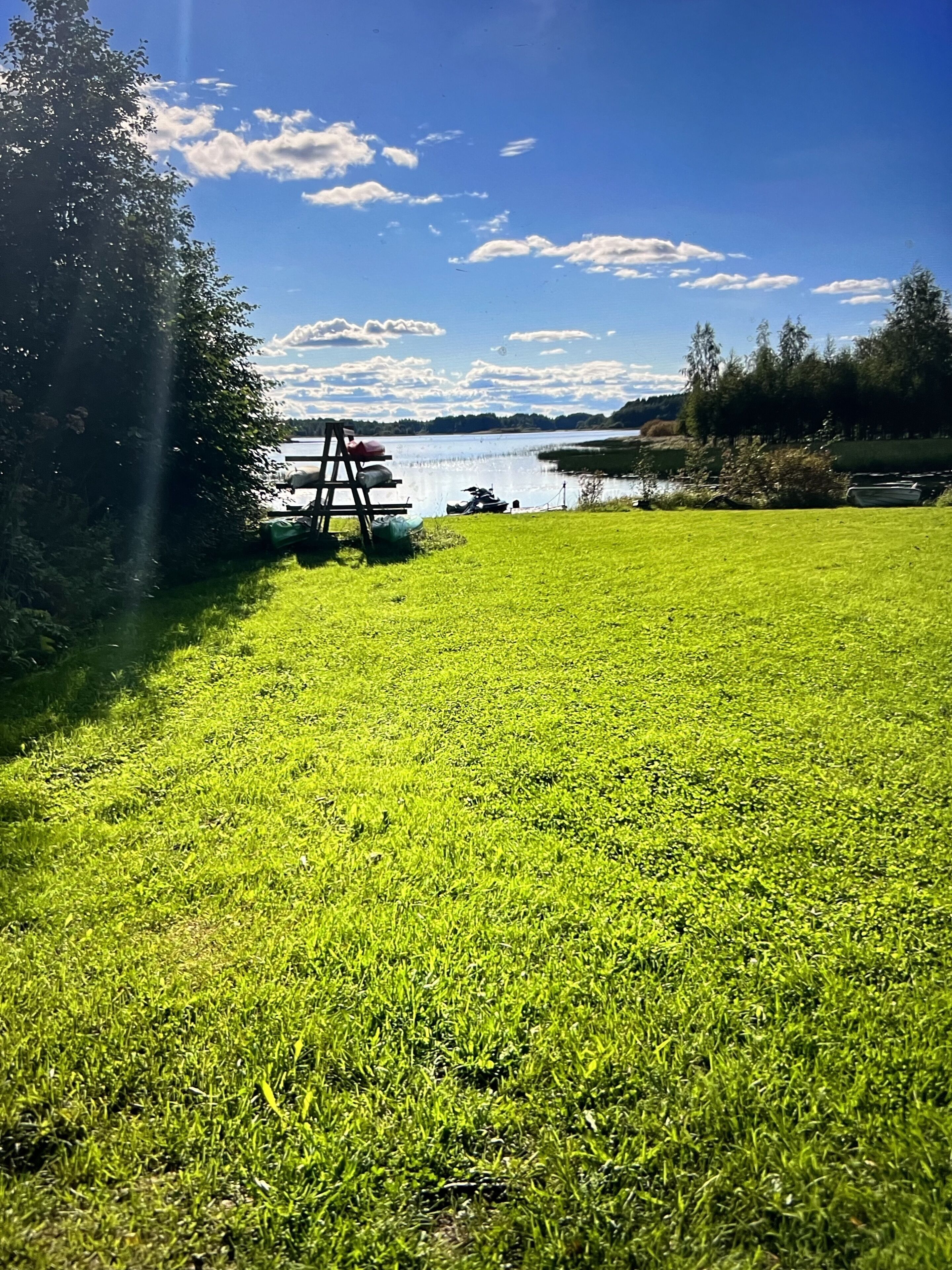 A grassy field with a swing set and a lake in the background.