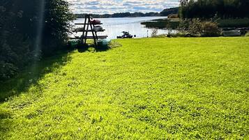 A grassy field with a swing set and a lake in the background.