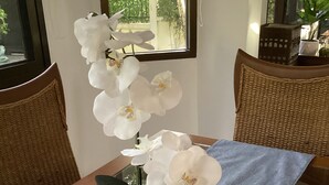 Una mesa de comedor con un jarrón de orquídea blanca, un camino de mesa azul y guijarros blancos.