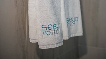A bathroom with a towel rack holding two white towels and a metal towel holder with three folded towels.
