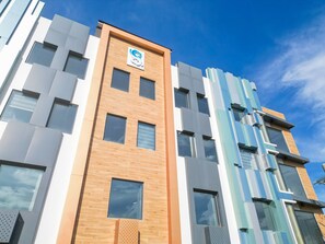A modern building with a prominent logo on the facade, multiple windows, and a mix of brick and glass materials. - Seeya Hotel (Tubigon)