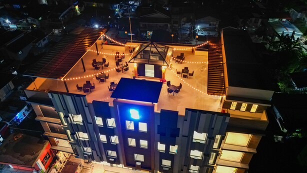 Een meerhoog gebouw met een dakterras, compleet met buitenmeubilair en lichtjes.