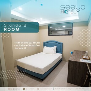 A standard room with a bed, a bedside table, a mirror, and a small desk. The room has a ceiling light and a view of the bathroom. - Seeya Hotel (Tubigon)