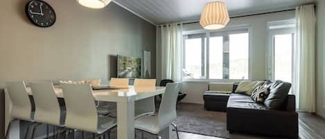 A modern living space with a dining area, a sofa, and a large window.