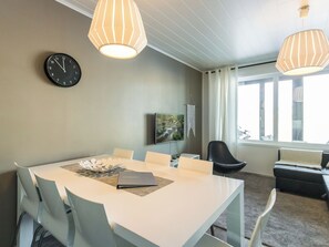Een moderne eetruimte met een tafel, stoelen, een klok en hanglampen.