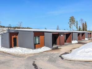 Une rangée de chalets modernes, avec un ciel dégagé et de la neige au sol.