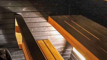 A wooden bench with a metal frame, positioned on a dark wooden floor with a reflective surface.