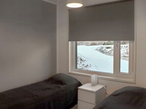 Ein Zimmer mit Fenster, einem Nachttisch und zwei Betten.