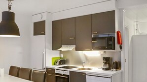 Una cocina compacta con encimera blanca, electrodomésticos de acero inoxidable y armarios marrones.