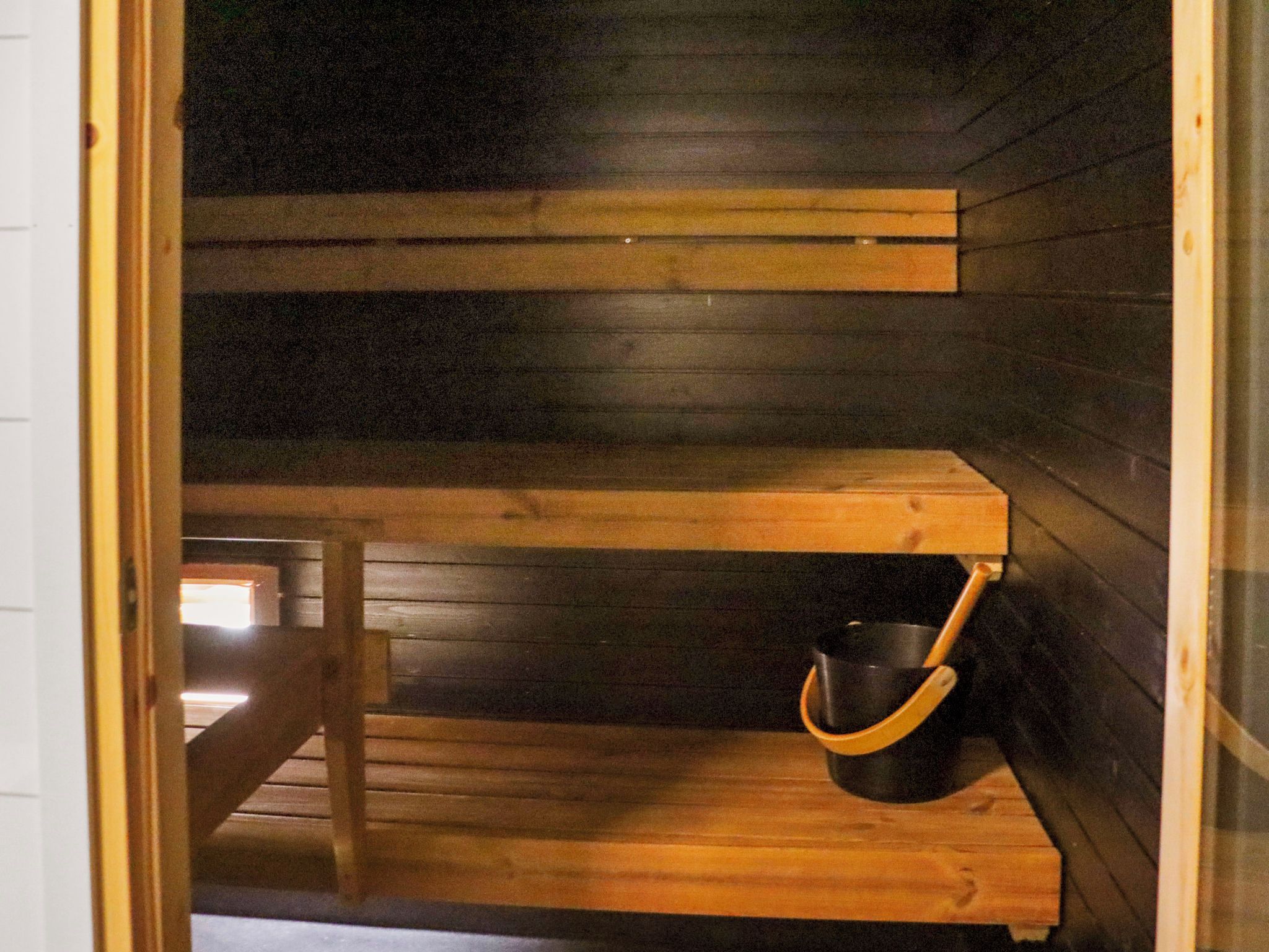 A wooden interior with a bench and a black bucket.