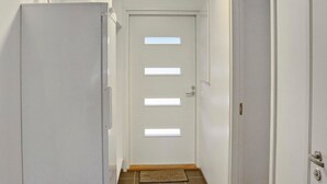 Un pasillo estrecho con una puerta blanca que tiene cuatro ventanas rectangulares.