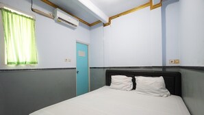Una habitación de hotel con una cama, una ventana con cortinas, un aire acondicionado y una puerta.