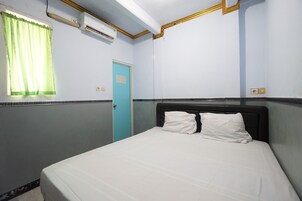 Una habitación de hotel con una cama, una ventana con cortinas, un aire acondicionado y una puerta.