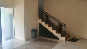A clean, modern interior with a staircase, tiled floor, and a trash bin. - OYO 93623 Assalam Homestay Syariah (Surabaya)