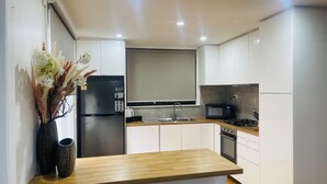 A modern kitchen with white cabinets, a stainless steel refrigerator, a microwave, a sink, and a wooden countertop. - Home in Sunshine  (Sunshine)