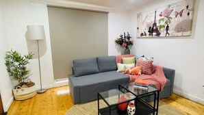 A living room with a grey sofa, a glass coffee table, a lamp, a plant, and a painting of Paris. - Home in Sunshine  (Sunshine)