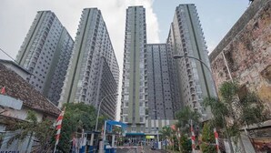 A high-rise residential building with multiple balconies, a gated entrance, and surrounding greenery. - Hotel O Apartment Grand Asia Afrika By Prisma (Bandung)