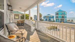 A covered porch with a view of a beach and two blue houses. - Gorgeous Sound-side Family Friendly Retreat l Golf Cart Included l Convenient to National Seashore (Navarre)