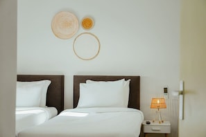 Una habitación de hotel con cama doble, mesita de noche con lámpara y decoración en la pared.