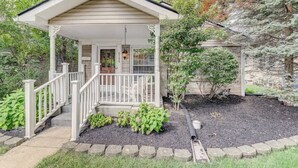 A house with a covered porch, a small garden area with mulch and plants, and a stone pathway leading to the entrance.