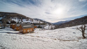 A wooden cabin with a sloped roof, surrounded by snow-covered hills and mountains. - Pleasant studio 4 ppl near the slopes (Allos)