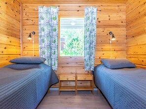 Eine Hütte mit zwei Einzelbetten, einem kleinen Tisch und Vorhängen mit einem Muster.