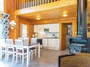 Ein Holzblockhaus-Interieur mit Essbereich, Küche und Kamin.