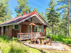 Eine Holzhütte mit Veranda, Holzmöbeln und Grill.