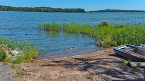 Un lac avec un bateau sur la rive, entouré de verdure et de quelques arbres en arrière-plan.