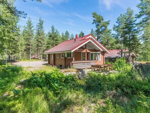 Une cabane avec un toit rouge, entourée d’une forêt dense.