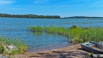 Un lac paisible, avec un bateau amarré sur la rive, entouré de verdure et d’arbres.