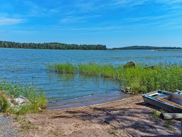 Een kalm meer met een boot afgemeerd aan de oever, omgeven door begroeiing en bomen.