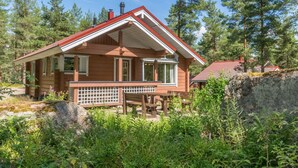 Une cabane en bois avec un toit rouge, entourée d’une forêt dense.