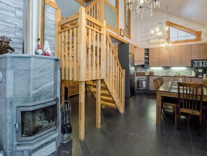 A modern kitchen with a wooden staircase, a fireplace, and a dining area.