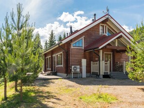 A wooden cabin with a chimney, a porch, and a satellite dish.