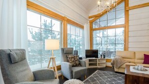Una sala de estar moderna con ventanas amplias, televisor y asientos cómodos.