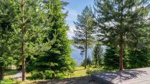 Una terraza de madera con vistas a un lago rodeado de densos árboles de con íferas.