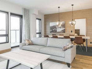 Uma sala de estar moderna com um sofá, uma mesa de centro e uma área de jantar com cadeiras e uma mesa.