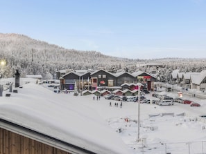 A snow-covered town with buildings, a parking lot, and a snowy hill in the background.